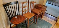 Three wooden chairs side by side: black Hitchcock chair, ladder back chair with rush seat, and shaker style chair with cane seat visible