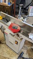 Full view of woodworking jointer on base showing infeed/outfeed tables and cutterhead guard