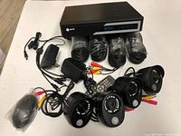 DVR unit, 4 security cameras, power adapters, video cables, and other accessories laid out on a table.