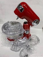 All components unboxed and displayed: mixer body, bowl and three attachments.