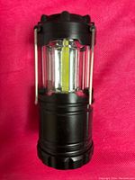 Front view of black camping lantern showing LED strips inside transparent panels.