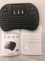 Mini 2.4GHz wireless keyboard with integrated touchpad, ergonomic button layout, and Lexma branding. Includes a user manual in English detailing product specifications and usage.