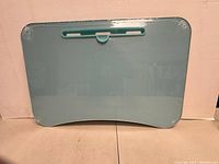 Front view of blue foldable table with smooth surface and central clip detail.