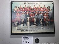 Full team photo laminated on plaque showing entire 1956-57 Montreal Canadiens team with trophies in front.