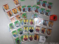 Photo of a spread of hockey cards with some labeled green stickers indicating numbers and markings. Cards are mostly from the Philadelphia Flyers, Chicago Black Hawks, and Montreal Canadiens.