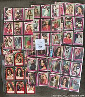 Top-down view of 46 Charlie's Angels cards laid out in plastic sleeves, showing images and captions from the TV series.