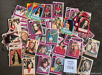 Photo showing assortment of Charlie's Angels cards and stickers laid out on surface, cards in pink borders and stickers colorful with stars and character portraits.