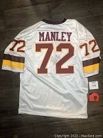 Back view of white Washington Redskins jersey #72 with stitched name 'MANLEY' and Dexter Manley signature on the number 72 area.