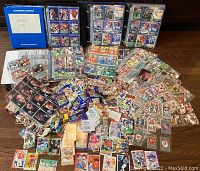 Wide view showing football cards spread out on a table with plastic sleeves, loose cards, and blue labeled binder for CFL cards from 1991.