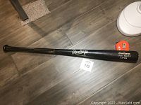 Full length view of the black Rawlings baseball bat lying flat to show overall condition and branding.