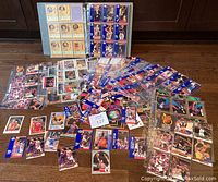Collection of basketball cards spread on floor including grouped cards in plastic pages and loose cards showing various players and styles from the early 1990s.