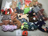 Full lot of 25 Ty Beanie Babies plush toys laid out on table showing variety and original tags.