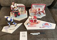Full lot of 4 figurines with hockey sticks and goalie nets on bases, showing players and bases with names and team logos.