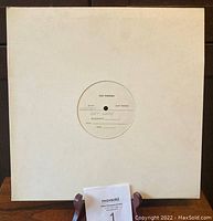 Full view of the white album cover with the test pressing vinyl inside. The cover shows some signs of staining and wear.