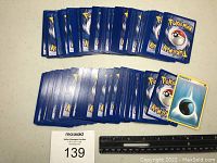 Collection of Pokemon cards showing card backs with Pokeball design and ruler for scale.