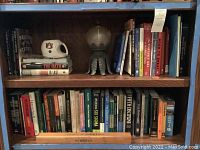 Books arranged on bookshelf with Auburn University mug on top, titles include 'The Oath' and 'Good To Great'.