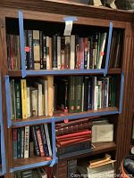 Four shelves of books with blue tape outlining included volumes