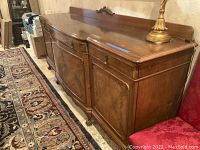 Full view of the wooden buffet sideboard with carved detailing, scratches and stains visible on the top.