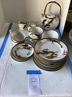 Full tea set showing teapot, creamer, sugar bowl, cups, saucers, and dessert plates arranged on a white surface