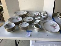 Overview of the full Bohemian china set including all plates, bowls, cups, sugar bowl, creamer, and platter on display.