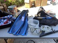 Overall view of dive gear laid out on table including fins, masks, snorkels, and bags