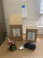 Two resin figurines, mushroom stingray and eggplant whale, displayed with their original boxes labeled 'Home Grown' behind them on a cardboard surface.