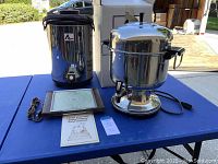 Full view of Farberware coffee server, Adcraft beverage dispenser, and Salton Hotray food warmer on blue table outdoors.