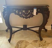 Full frontal view of the carved front apron and curved legs of the wooden foyer table.