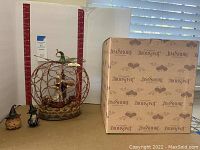 Photo of the wire pumpkin centerpiece alongside the two small figurines and the Jim Shore branded box behind.