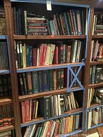 Wide view of book shelves showing medical books within blue taped boundaries on four shelves. Various titles and colors visible.