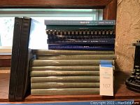 Photo of stacked medical books with visible titles including American College of Surgeons SESAP and Ciba Collection.