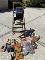 Full view of 4-step wood ladder with assorted hardware items on ground in front.