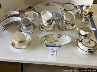 Overall view of assorted bone china cups, saucers, sugar and creamer, decorative bells, and other pieces