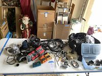 Wide view of table showing assorted cables, wires, guitar effects pedals, hardware, and bags.