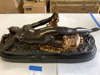 Full-length side view showing dark bronze reclining nude figure on oval base