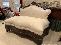 Full view of the off white brocade sofa showing ornate wood trim and curved design.