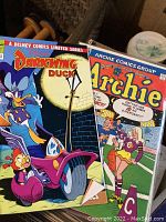 Two comic books shown: Darkwing Duck (Disney) and Archie (Archie Comics) covers visible.