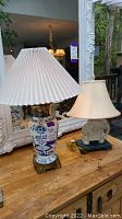 Photo showing both lamps on a wooden table in front of a large ornate mirror, capturing both lamps.