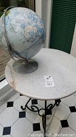 Photo of white round marble table with metal base and globe on top showing overall lot contents.