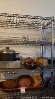 Photo showing the shelving unit loaded with various kitchen items including pots and wooden bowls, illustrating shelf structure and materials.