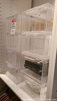 Stacked transparent plexiglass drawers showing medium size drawers with small items inside.