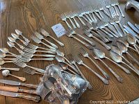 Wide layout of assorted silver-plate forks, spoons, knives and sterling collector spoons with various patterns and sizes.
