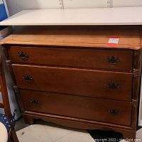 Front view of the vintage wooden dresser showing three drawers and metal handles