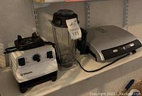 Overview of Vitamix blender base, pitcher and George Foreman grill on shelf