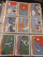 Open binder page showing nine Looney Tunes hologram cards featuring various characters in comic strip format painted with vibrant colors.