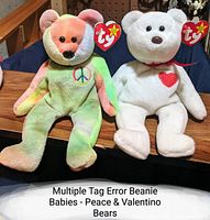 Photo of two Ty Beanie Babies bears, Peace and Valentino, sitting side by side showing their plush bodies and Ty heart tags.