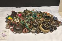 Photo showing a large pile of mixed broken jewelry including bracelets, necklaces, earrings, and beads in various colors and materials.