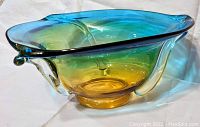 Side view of ombre glass bowl showing blue to amber gradient with clear glass accents on edge.