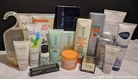 Front view of various Avon skincare, body care, and cosmetic products arranged in rows showing tubes, bottles, jars, and boxes.