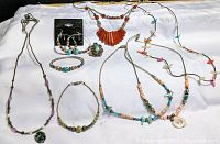 Top down view of the full lot showing all jewelry pieces including necklaces, bracelets, earrings, and a ring arranged on white fabric.